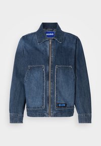 Jachetă din denim de culoare bleu închis, cu guler și fermoar frontal. Are două buzunare mari aplicate cu margini desfăcute și un eticheta HUGO albastră.