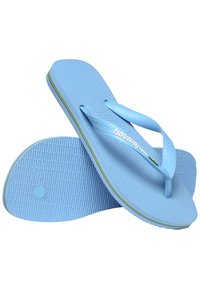Siniset kumiset flip-flopit, joissa on teksturoitu pinta, ohuet hihnat ja valkoinen logo. Pohjan reunoilla on keltainen ja vihreä korostusnauha.