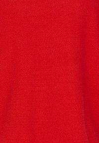 Roter Stoff mit strukturierter Oberfläche, der ein gleichmäßiges Webmuster zeigt. Die Farbe ist leuchtend und kräftig, ohne weitere Akzente.