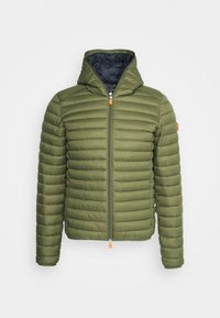 Giacca imbottita verde oliva con cappuccio, chiusura frontale con cerniera e un tirante arancione, e texture trapuntata. Fodera interna nera visibile.
