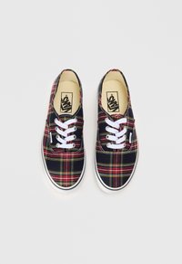 Plekkidega lõuendist tossud, millel on tumesinine taust punaste ja kollaste triipudega, valged nöörid ja kummist talla. Sildistus keelal.