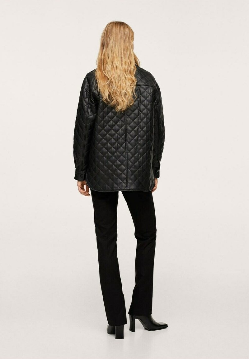 Pikowana czarna skórzana kurtka z zaokrąglonym hemem, długimi rękawami i detalami w postaci guzików, w zestawie z czarnymi spodniami i botkami na obcasie.