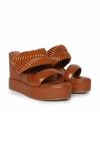 Sandalias de plataforma marrones con una textura brillante, que cuentan con una gruesa tira trenzada y un diseño de punta abierta, reposando sobre un sólido tacón de cuña.