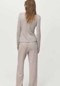 Lichtgrijs gebreid loungewear-set bestaande uit een top met lange mouwen en wijde pijpen, met een gladde textuur en een relaxte pasvorm.