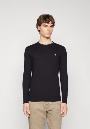 Pull en maille noir à manches longues et col côtelé. Doté d'un petit logo jaune sur la poitrine. Tissu texturé et coupe ajustée.