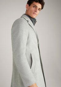 Abrigo de mezcla de lana gris claro con un diseño estructurado, que presenta solapas de muesca y bolsillos laterales. Textura suave y perfil ajustado.