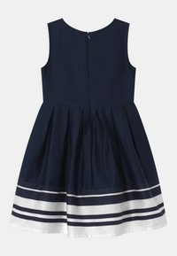 Navy modré šaty bez rukávů s plisovanou sukní, se bílým a navy pruhovaným lemem a zapínáním na zip vzadu. Vyrobené z hladké tkaniny.