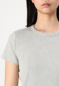 Grå ribbet t-shirt med korte ærmer, rund halsudskæring og en blød tekstur. Har et tætsiddende udseende, der passer til afslappet tøj.