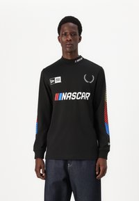 Svart langermet skjorte med NASCAR-logo og fargerike striper i rødt og blått på ermene. Har høy krage. Laget av bomullsblanding.