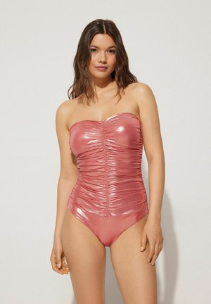 Bañador rosa sin tirantes con una textura brillante y fruncida, que presenta un corsé ajustado y una parte inferior lisa y de corte alto, creando una silueta aerodinámica.