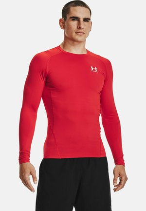 Rød langærmet træningsshirt lavet af strækbart materiale med flade sømme og rund halsudskæring. Lille hvidt logo på brystet.