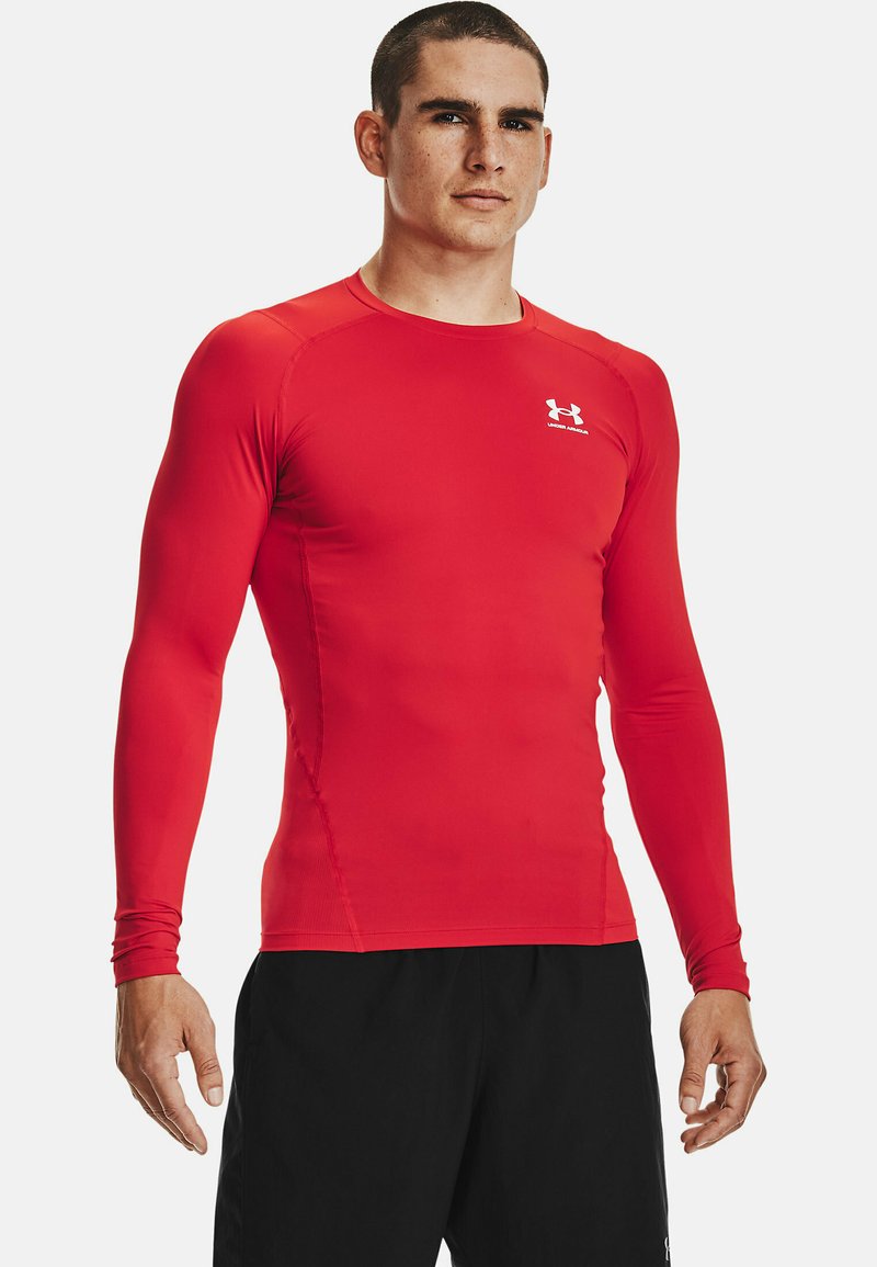 Rød langærmet træningsshirt lavet af strækbart materiale med flade sømme og rund halsudskæring. Lille hvidt logo på brystet.