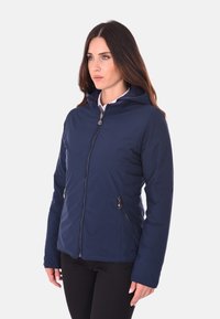 Giacca isolante blu navy con cappuccio, chiusura frontale a zip e due tasche laterali. Tessuto liscio e design aderente.