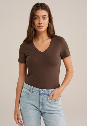 Brun V-ringad t-shirt i mjukt, stretchigt tyg med korta ärmar, i kombination med ljusblå denimjeans, vilket visar en avslappnad stil och enkelhet.