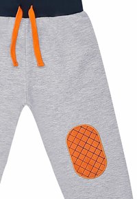 Graue Jogginghosen mit elastischem Taillenbund, orangefarbenen Kordeln und einem orangefarbenen gesteppte Patch am Knie. Weicher Stoff.