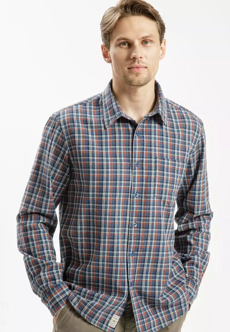 Koszula w kratę na guziki w kolorze niebieskim, czerwonym i białym. Długie rękawy, kołnierz, lekki materiał z kieszonką na piersi i szczegółowym oznaczeniem z boku.