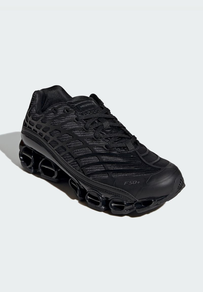 Chaussure de sport noire avec une tige en mesh, un design texturé et une semelle épaisse et arrondie avec des trous de ventilation visibles.