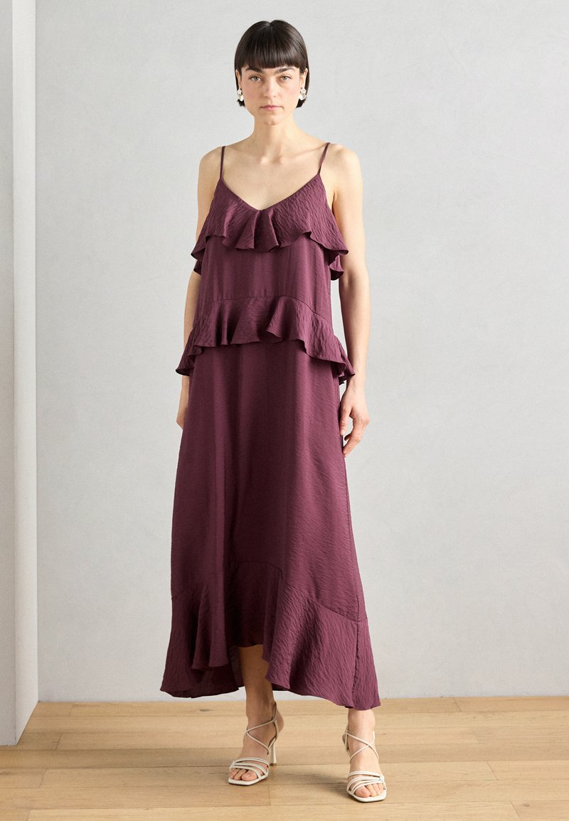 Burgunderfarbenes Maxikleid mit gestuften Rüschendetails, Spaghettiträgern und fließender Silhouette, gefertigt aus leichtem Stoff mit texturierter Oberfläche.