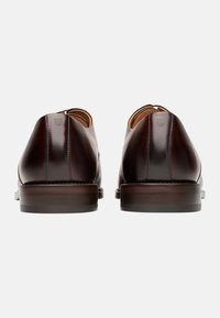 Braune Leder-Dressschuhe mit glatter Oberfläche, runder Zehenpartie, dezenten Stickereien und einer Holzsohle. Ohne zusätzliche Verzierungen entworfen.