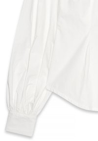 Witte blouse met lange mouwen en volumineuze pofmouwen, recht gesneden aan de onderkant. Gemaakt van zachte stof met een knoopsluiting bij de manchetten.