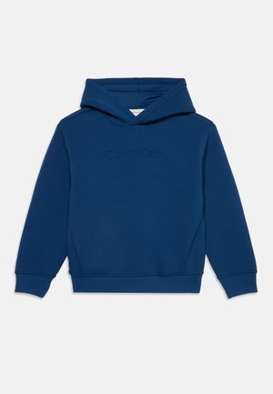 Tumesinine kapuutsiga pusa pikkade varrukate ja esitaskuga, mille rinnal on peenelt reljeefne Calvin Kleini logo.