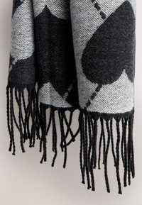 Wool blend scarf featuring a grey background with large black heart patterns, finished with black fringed edges and a textured weave.