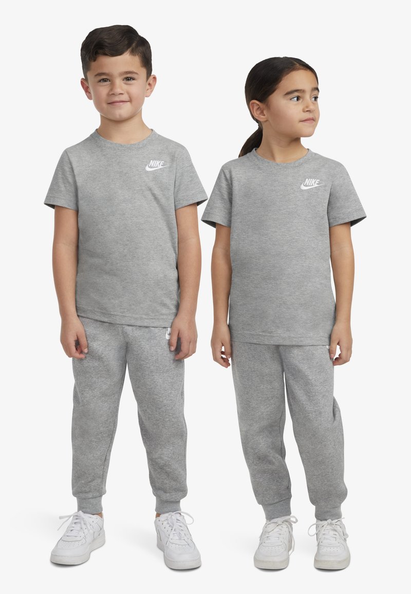 Sive bombažne majice in trenirke z rebrastimi manšeti; oboje ima majhen bel Nike logotip na levi strani prsnega koša.