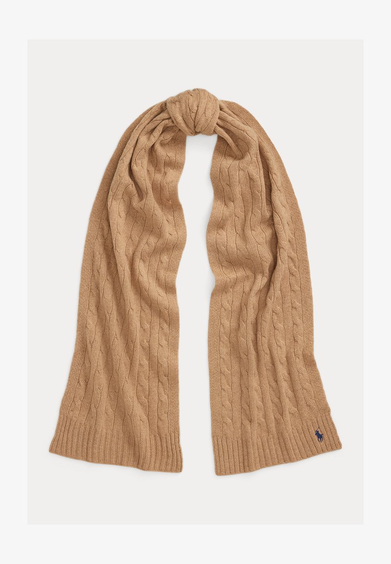 Lys brun strikket skjerf med flettemønster, ribbekanter og lite brodert marineblått logo nær den ene enden.