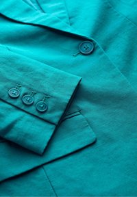 Turkusowy lniany blezer z klapami, zapinany na jeden guzik, z mankietem zdobionym czterema guzikami i delikatną teksturą.