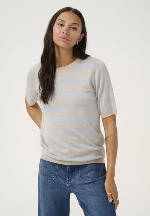Pull court beige clair à manches courtes avec des rayures horizontales bleues. Texture douce, col rond et coupe légèrement ample. Associé à un jean bleu.