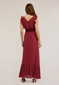 Burgunderfarbenes Maxikleid mit V-Ausschnitt, Rüschensäumen, gerafftem Taillenbund und plissiertem Saum. Glatte Textur und fließendes Design.