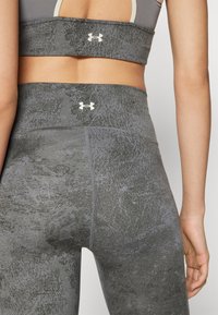 Gray athletic leggings with a textured pattern and high waistband. Features Under Armour logo in light color on the back. Smooth fabric.