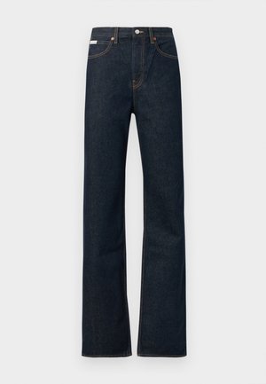 Tmavomodré denimové rifle so strihanými nohavicami, obsahujú oranžové prešívanie, zapínanie na predné gombíky a malú nálepku na páse.