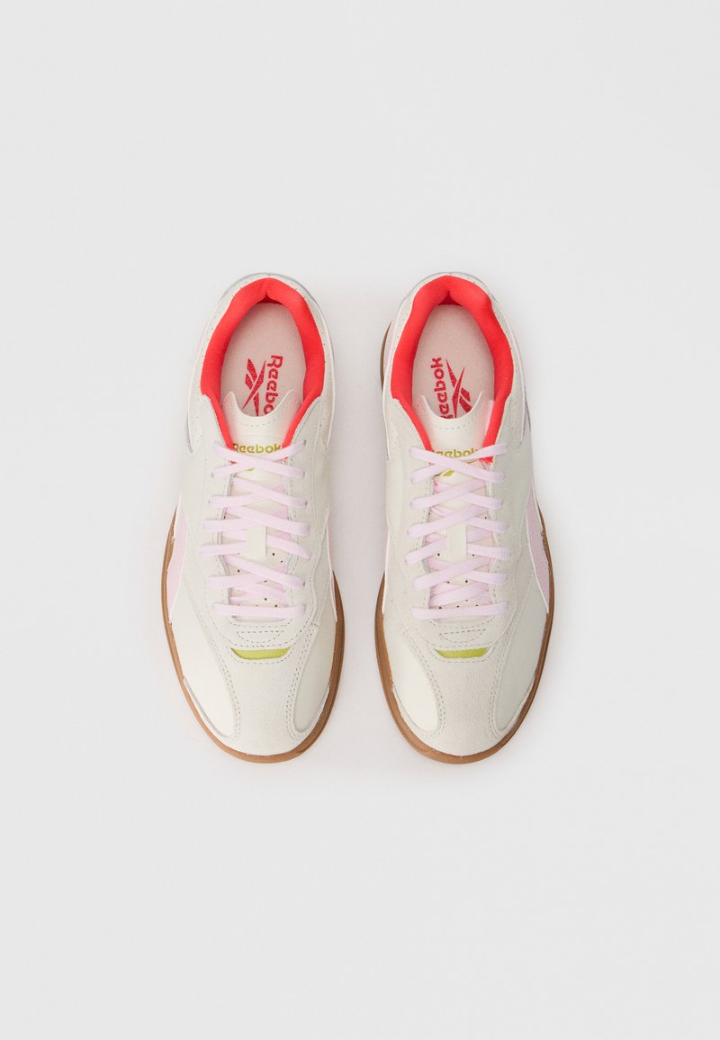 Sneakers bianchi con lacci e dettagli rosa, dotati di suola in gomma. I materiali comprendono pelle e camoscio, con un logo sulla linguetta.