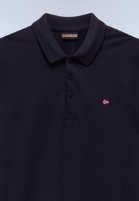 Marineblå polo med korte ermer, tre-knaps placket, ribbet krage og et liten brodert norsk flagg på brystet.