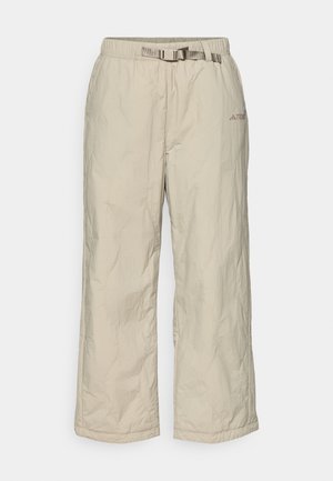 Vaate ulkona beige väri, löysä malli, joustava vyötärö ja säädettävä vyö. Valmistettu kevyestä, teksturoidusta materiaalista. Ei näkyviä taskuja.