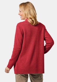 Roter gestrickter Cardigan mit lockerer Passform, ausgestattet mit gerippten Bündchen und Saum, entworfen für Komfort und Wärme. Keine sichtbaren Beschläge oder Muster.
