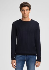 Sweatshirt en maille bleu marine avec un devant textur�é, encolure ronde côtelée et manches longues. Associé à un jean en denim ajusté.
