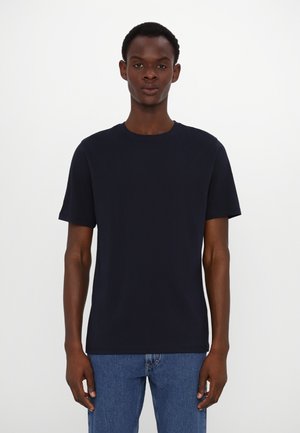 T-shirt bleu marine à manches courtes avec un col rond, fabriqué en tissu coton doux, associé à un jean en denim bleu clair.