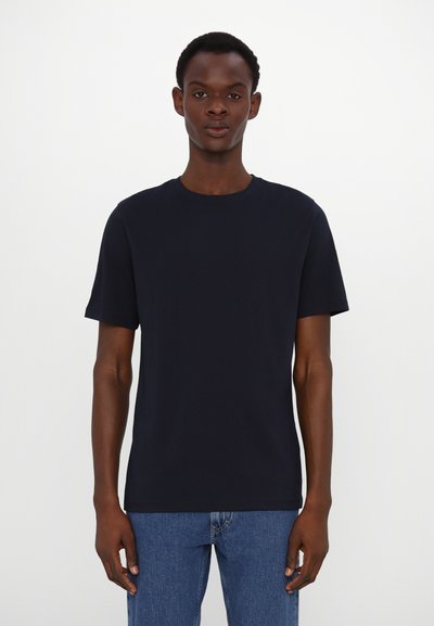 T-shirt bleu marine à manches courtes avec un col rond, fabriqué en tissu coton doux, associé à un jean en denim bleu clair.