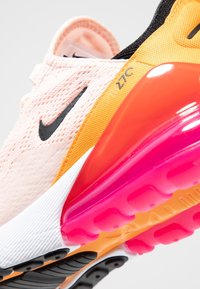 Tenisky Nike Air Max s lehkým růžovým síťovaným svrškem, oranžovými a černými akcenty, a robustní podrážkou s průhlednou růžovou vzduchovou jednotkou.