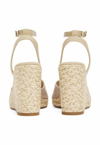 Sandali wedge beige con suole in corda intrecciata, pannelli laterali in tessuto e cinturini alla caviglia regolabili. Finitura testurizzata con dettagli in hardware dorato.