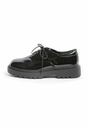 Scarpa stringata in pelle verniciata nera con suola spessa scanalata, tacco basso e punta arrotondata, vista dal lato esterno su sfondo bianco.