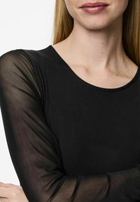 Černý top s kulatým výstřihem a dlouhými rukávy vyrobený z průhledného materiálu, který kontrastuje s pevným texturou těla.