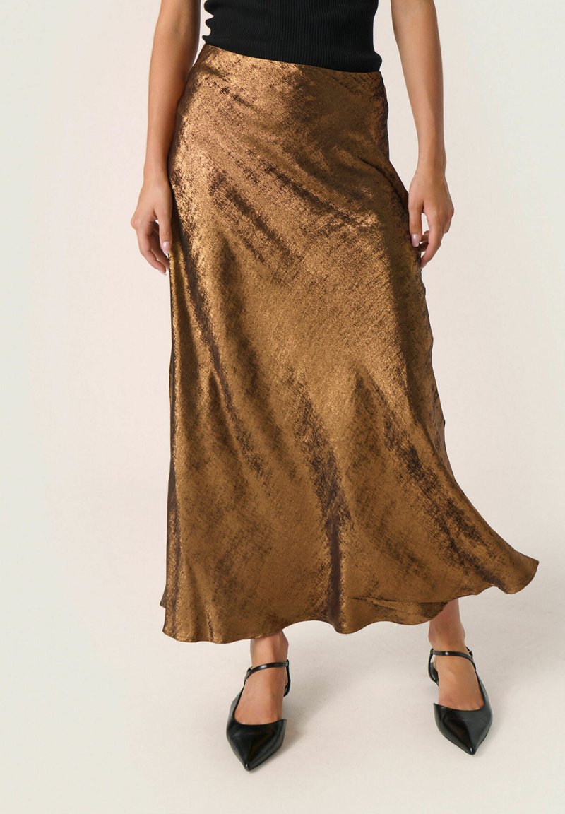Gonna maxi in satin bronzo con una texture liscia e una leggera lucentezza. Presenta un taglio dritto con un orlo fluido. Abbinata a scarpe nere a punta.