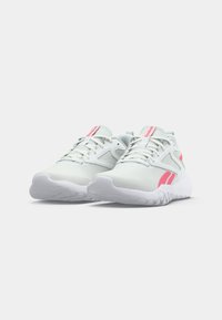 Încălțăminte sport albă cu accente roz, suprafață din plasă texturată, design de susținere și talpă flexibilă albă, având șireturi și detalii de brand.