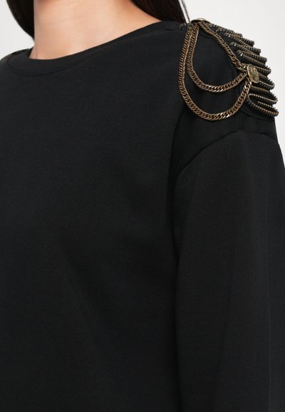Czarna bluza z okrągłym dekoltem, długimi rękawami i dekoracyjnymi łańcuchami na ramionach, wykonana z miękkiego materiału o gładkiej teksturze.
