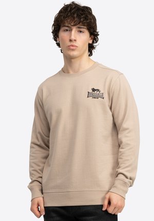 Beige, langærmet sweatshirt lavet af blødt stof, med rund halsudskæring og et lille sort broderet logo på brystet.