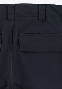 Pantaloni blu navy scuro con una texture liscia, dotati di tasche posteriori e passanti per cintura. Design semplice con cuciture uniformi in tutto il capo.