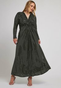 Zwarte maxi-jurk met lange mouwen, V-hals, gathers in de taille en zilveren pailletten horizontale strepen. Doorzichtige stof met een vloeiende silhouet.